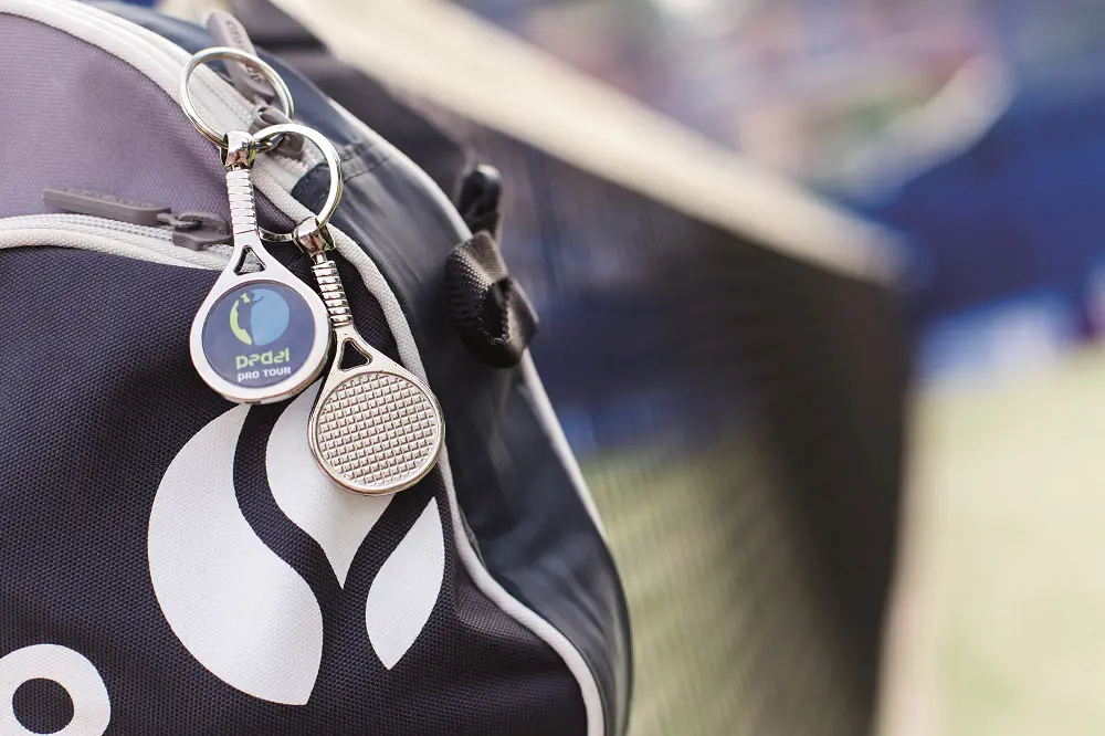 Llavero de pádel metálico sobre una bolsa de deporte de padel.