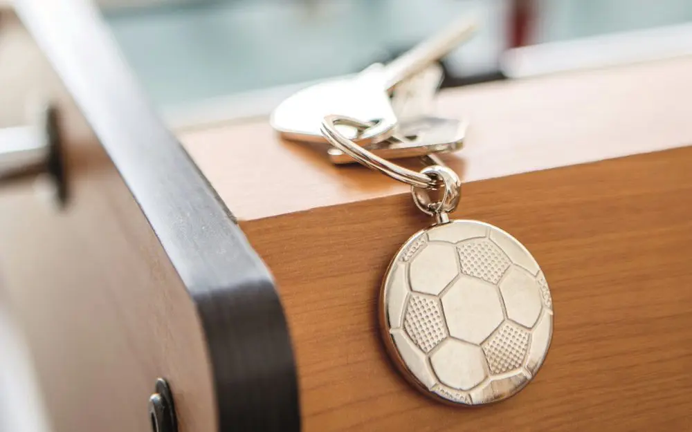 Llavero metálico con forma de balón de fútbol sobre un futbolín